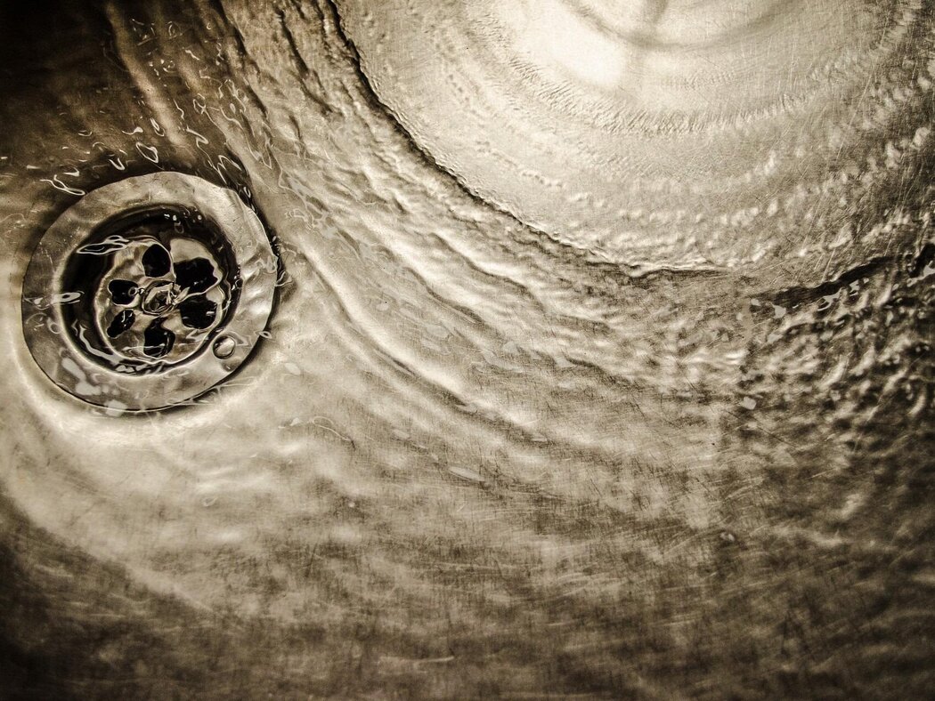 Wasser läuft in einem Edelstahl-Spülbecken in den Abfluss.
